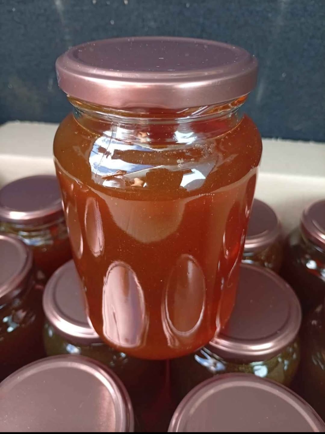 Pote de mel silvestre dourado com colher de madeira
